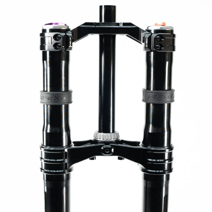 Black dual mountain bike suspension fork with clamps and adjustment knobs.